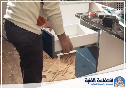 افضل شركة صيانة مطابخ في الشارقة وام القيوين فني شركة صيانة مطابخ في الشارقة وأم القيوين أثناء إصلاح خزائن المطبخ وتحسين الإغلاق
