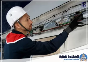 فني متخصص يفحص الأسلاك ولوحة التحكم أثناء تصليح ابواب اتوماتيك في راس الخيمة لمعالجة الأعطال.