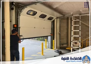 فني يفحص باب جراج علوي خلال تصليح ابواب اتوماتيك في أم القيوين لمعالجة أعطال الفتح والإغلاق.