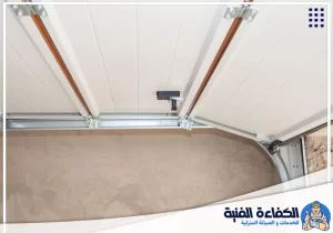 تظهر تفاصيل مسارات وحوامل باب الجراج العلوي وفحصها عند صيانة الأبواب الأوتوماتيكية بأم القيوين.