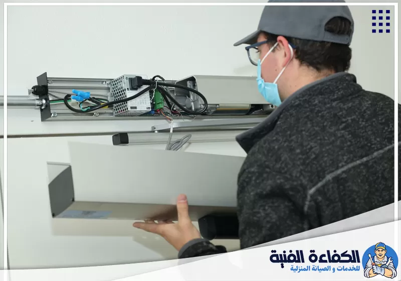 فني يفحص لوحة التحكم والتوصيلات بمشغل الباب ضمن صيانة مواتير الأبواب الأوتوماتيكية بأم القيوين.